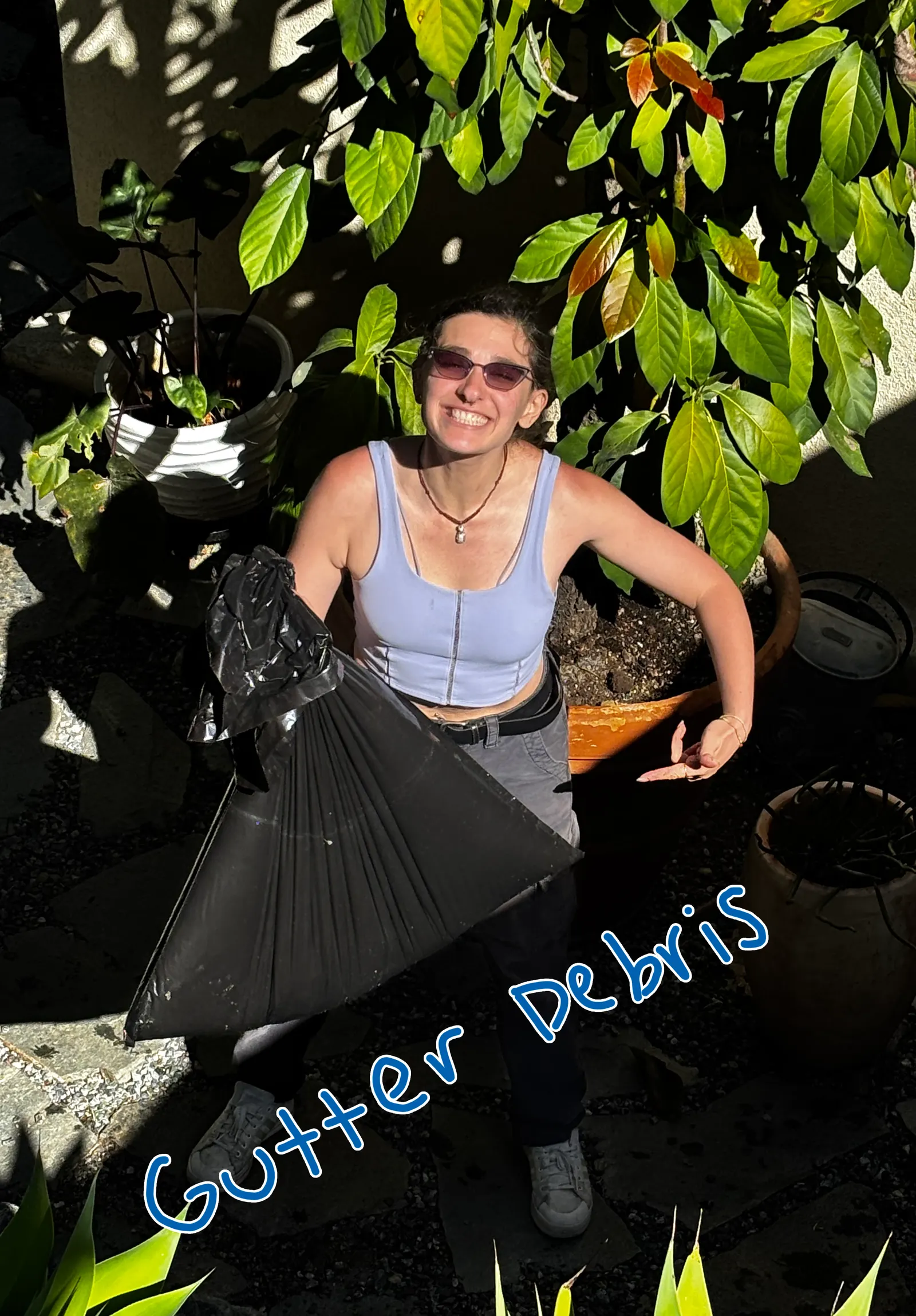 A Happy Gator team member holding a bag of debris cleared out of a customer's gutters