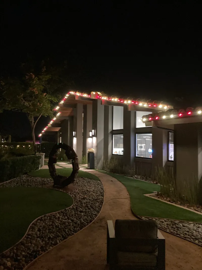 Red and warm white bulbs running along a home's stepped roofline at night